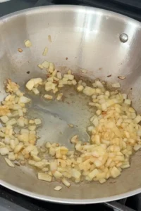 Diced onions and garlic sautéing in oil in a large pan.