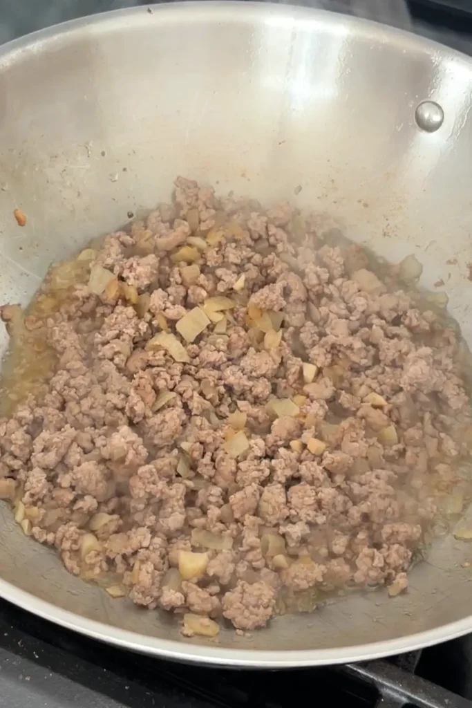 Ground pork cooking and browning with onions and garlic.