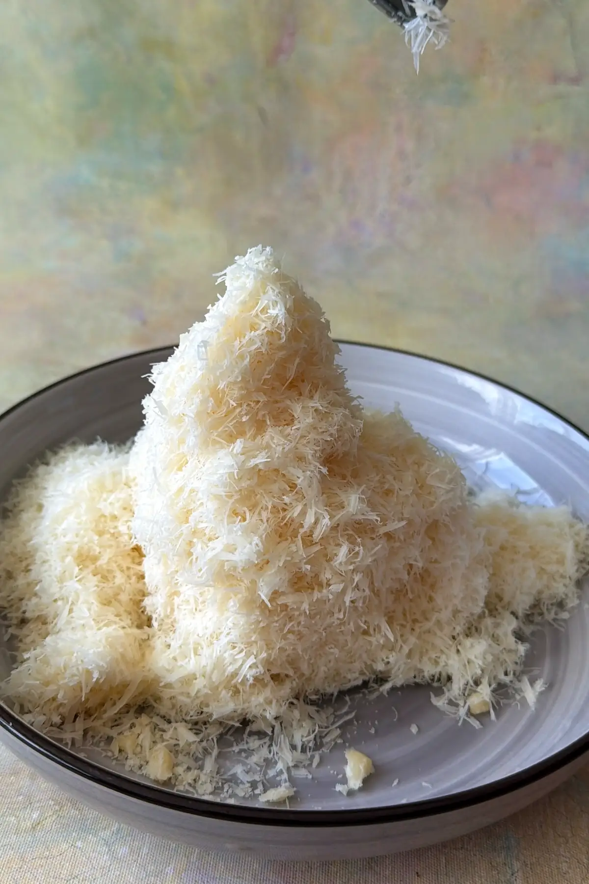 Grated Parmesan cheese piled high on a gray plate.
