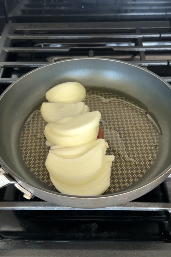 Freshly sliced onions added to a pan with oil before cooking