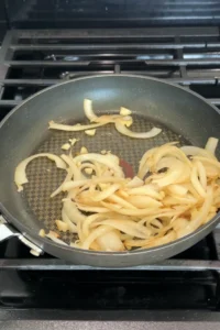 Sliced onions and garlic sautéing in a pan until soft and lightly caramelized.