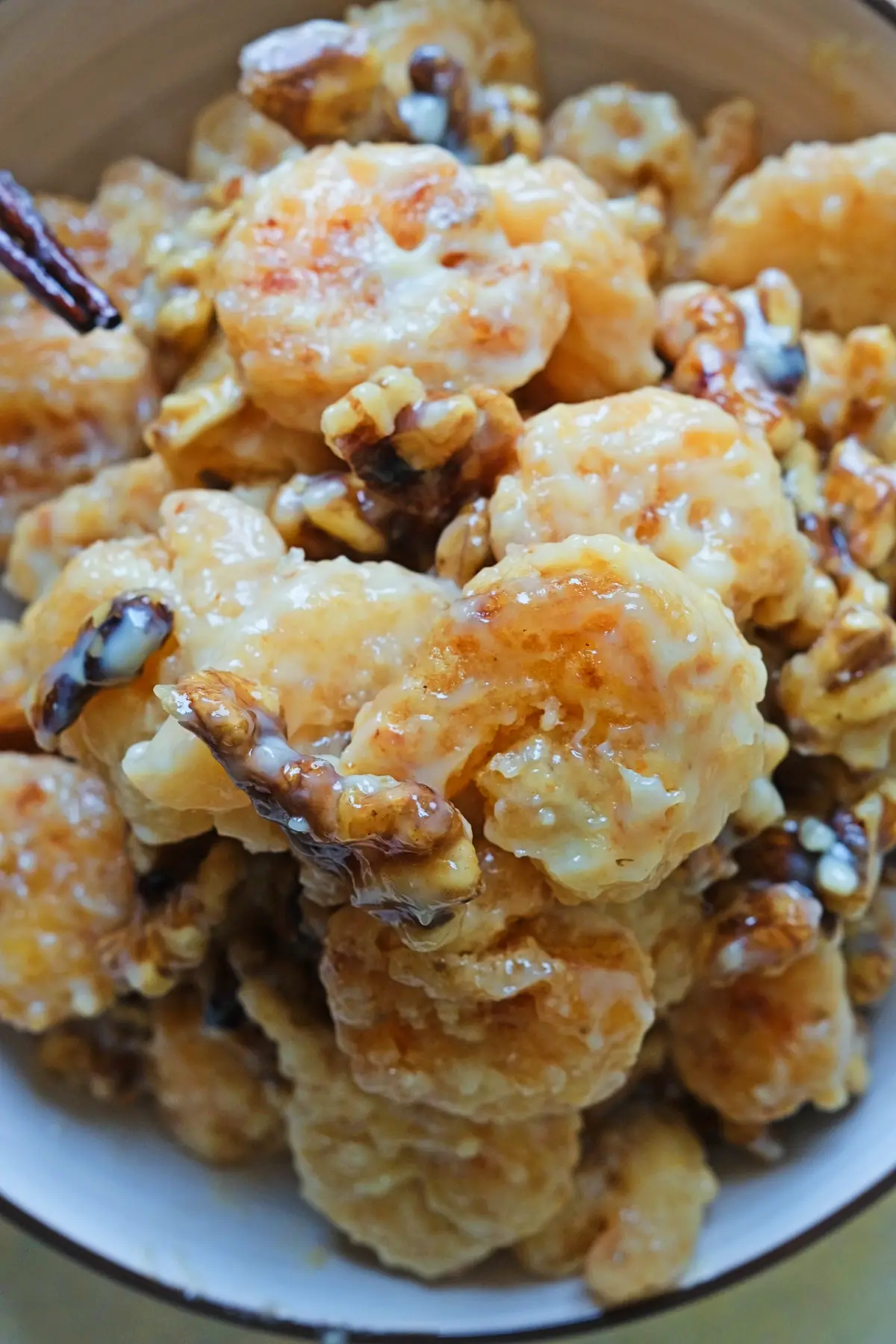 Bowl of crispy honey walnut shrimp coated in a creamy sauce, with golden fried shrimp pieces and candied walnuts mixed throughout.