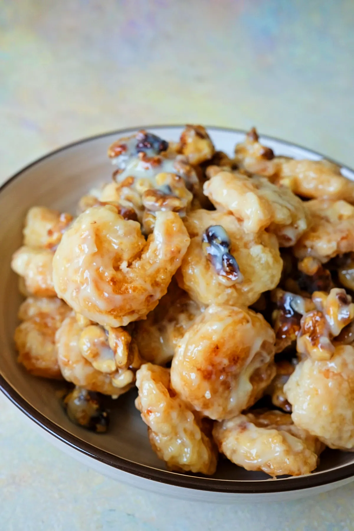 Front-facing view of honey walnut shrimp in a shallow bowl, with glossy sauce pooling slightly and caramelized walnuts scattered throughout.
