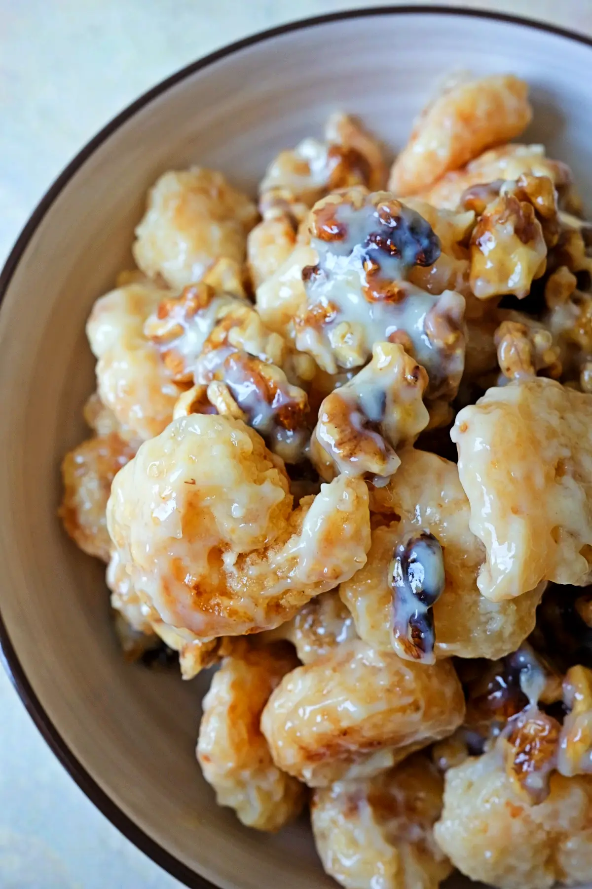 Close-up of saucy honey walnut shrimp piled in a bowl, emphasizing the creamy coating and toasted walnuts nestled between shrimp pieces.