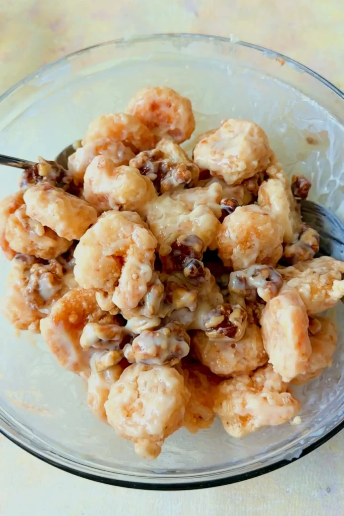 Honey walnut shrimp fully coated in creamy sauce with caramelized walnuts mixed throughout in a serving bowl