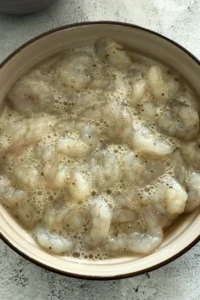 Close-up of shrimp soaking in whisked egg whites.
