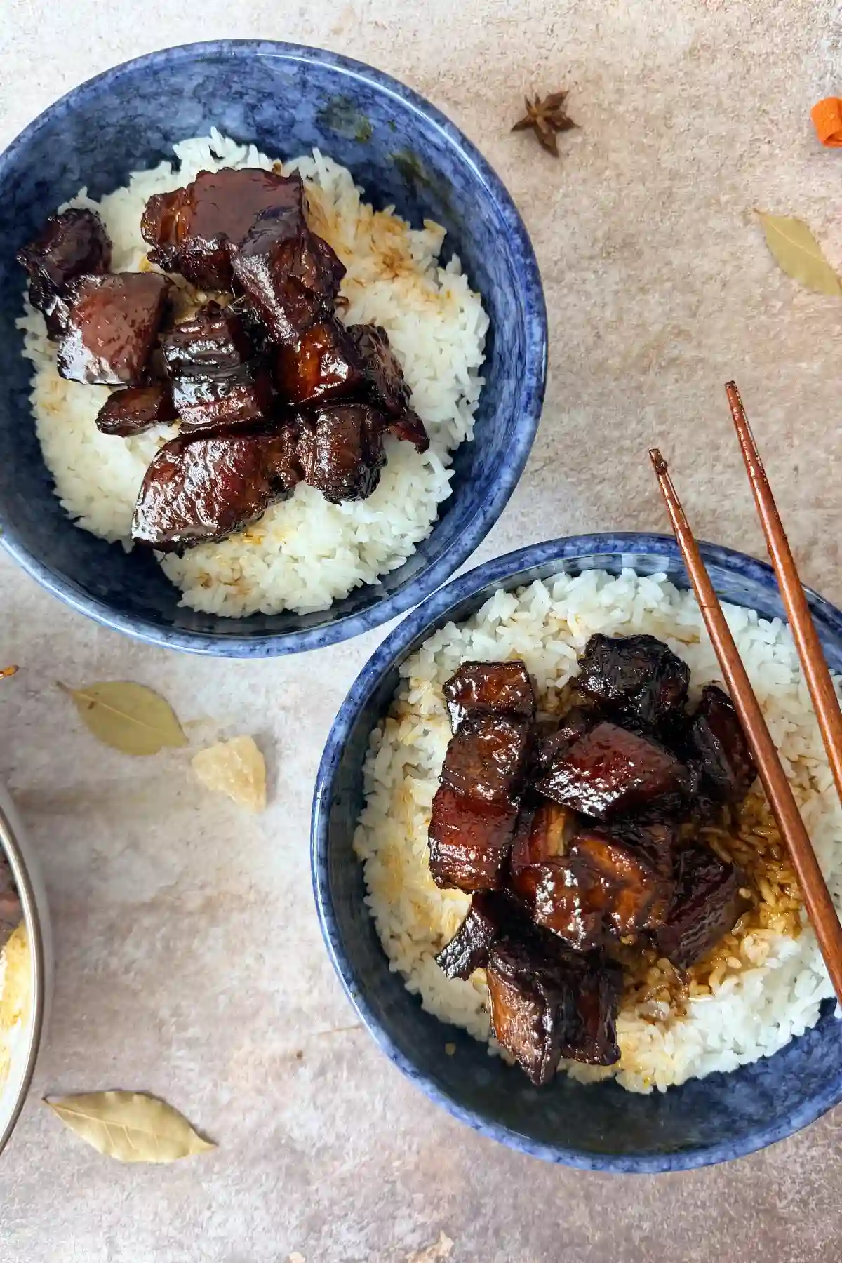 Two bowls of Chinese braised pork belly over rice with chopsticks