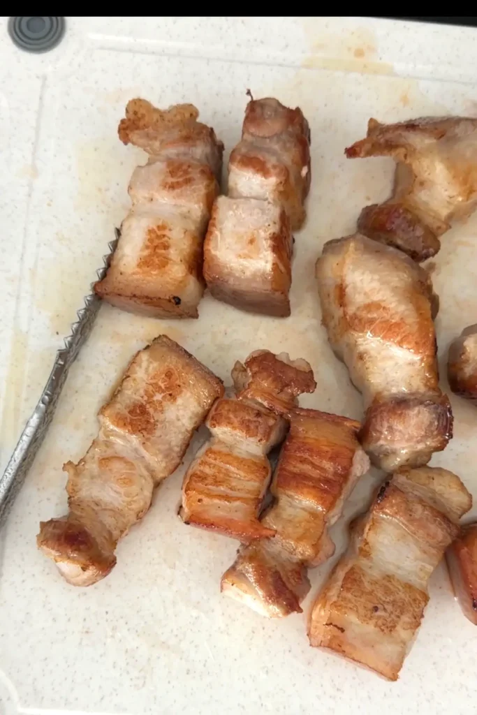 Golden browned pork belly pieces on cutting board for braised pork belly