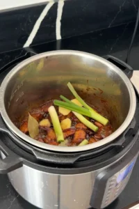 Adding ginger and green onions to braised pork belly in Instant Po