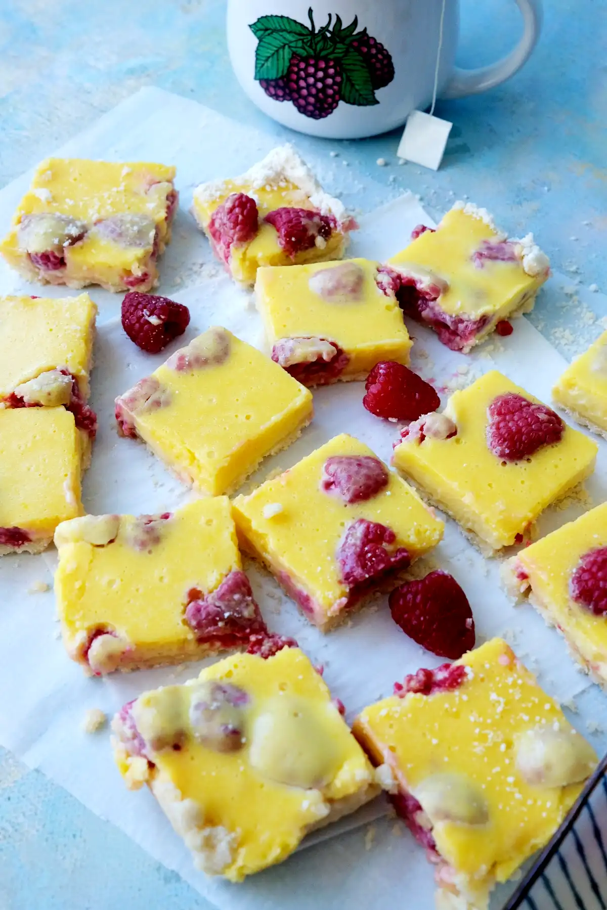 Raspberry lemon bars cut into squares with fresh raspberries baked into the creamy lemon filling.