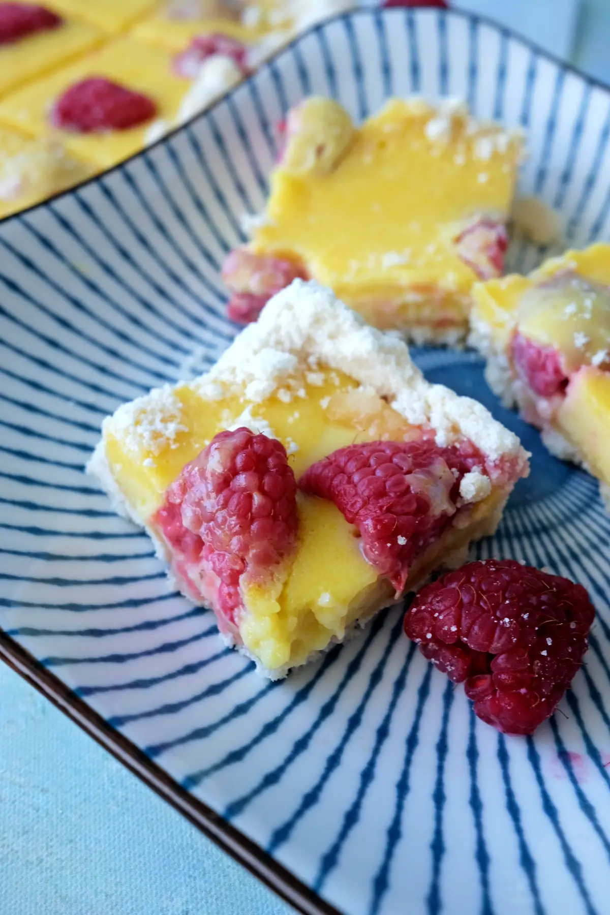 Close-up of raspberry lemon bar showing creamy lemon filling and buttery crust.
