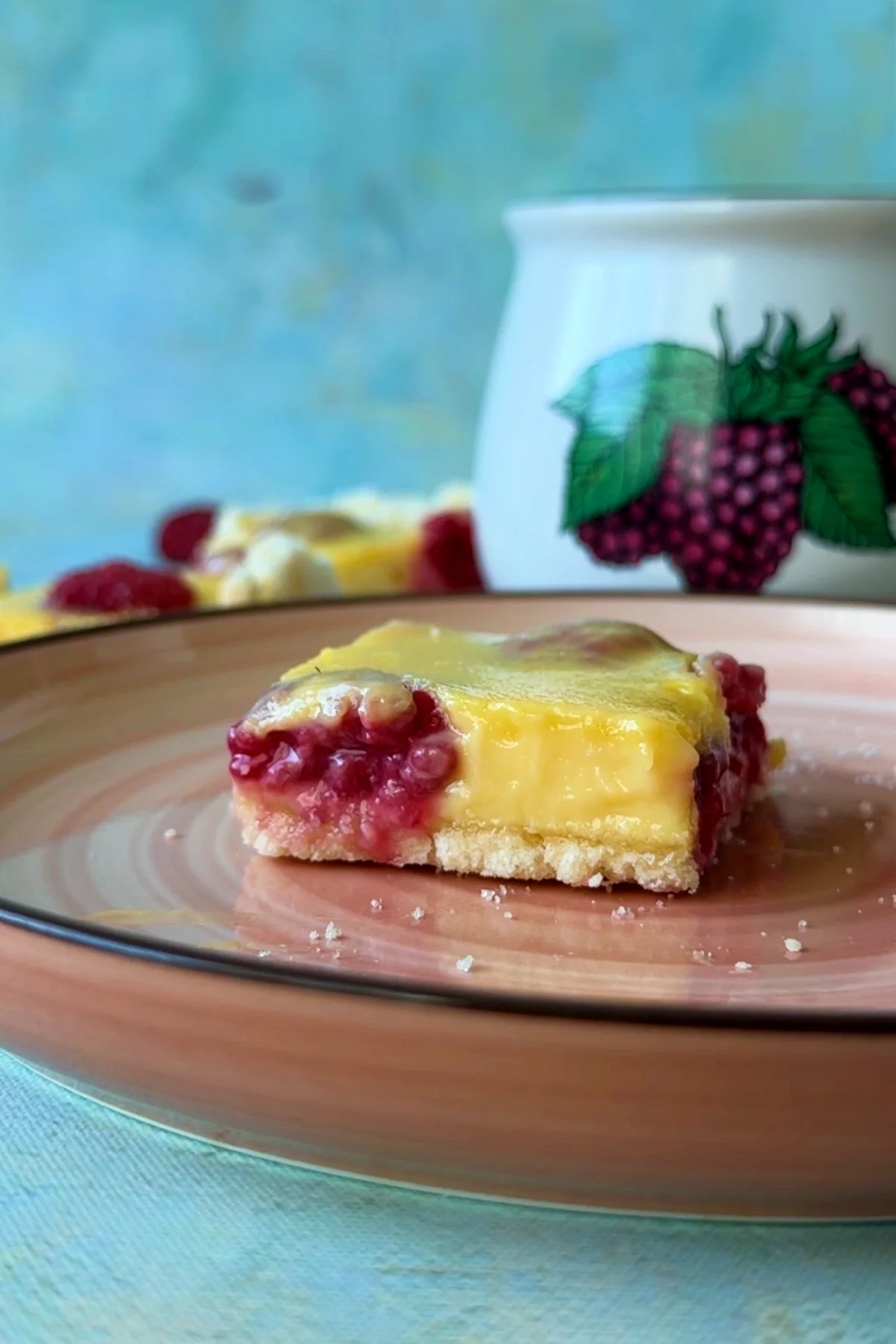 Close-up of a raspberry lemon bar showing the smooth lemon filling and buttery shortbread crust.