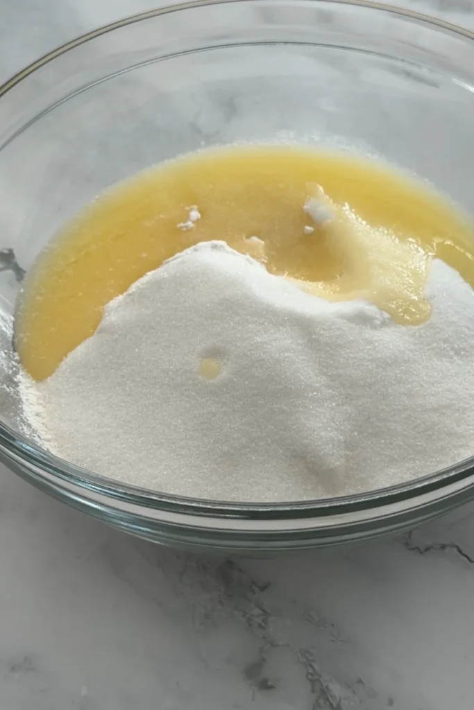 Melted butter and sugar mixed with flour to make the shortbread crust for raspberry lemon bars.