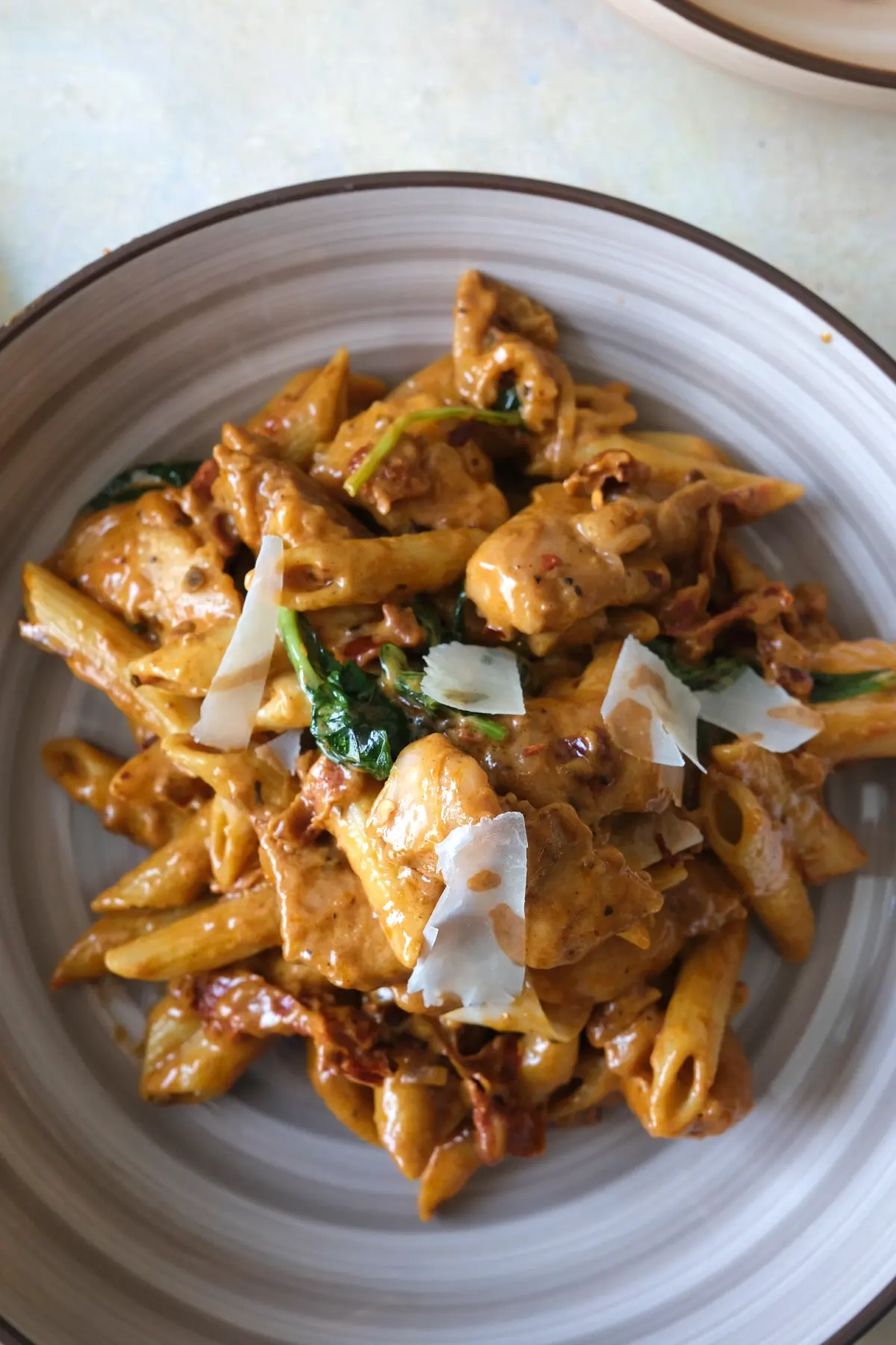 Plate of marry me chicken pasta with juicy chicken, creamy parmesan sauce, sun-dried tomatoes, and basil.