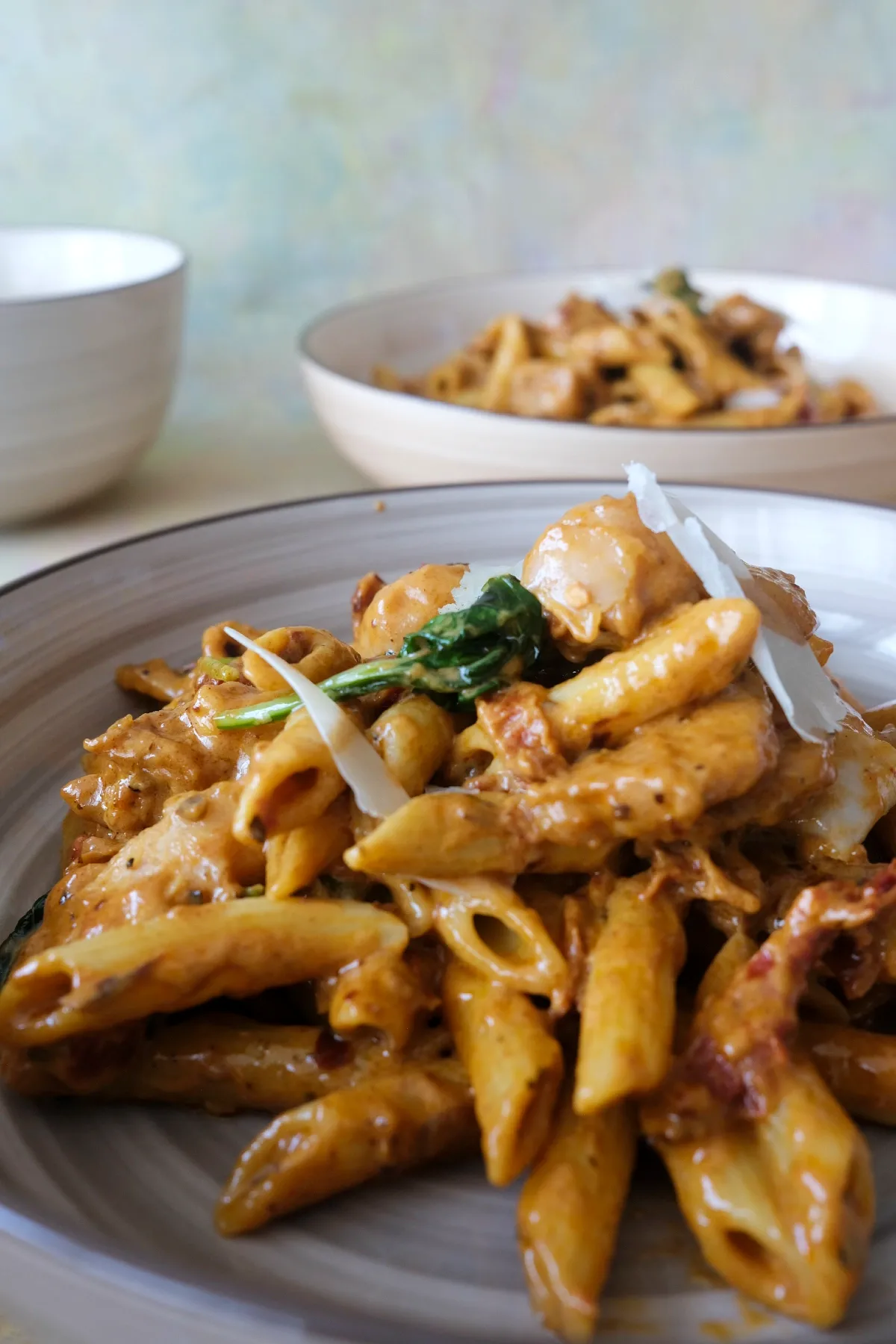 Creamy marry me chicken pasta served in a bowl with penne, chicken, basil, and parmesan.