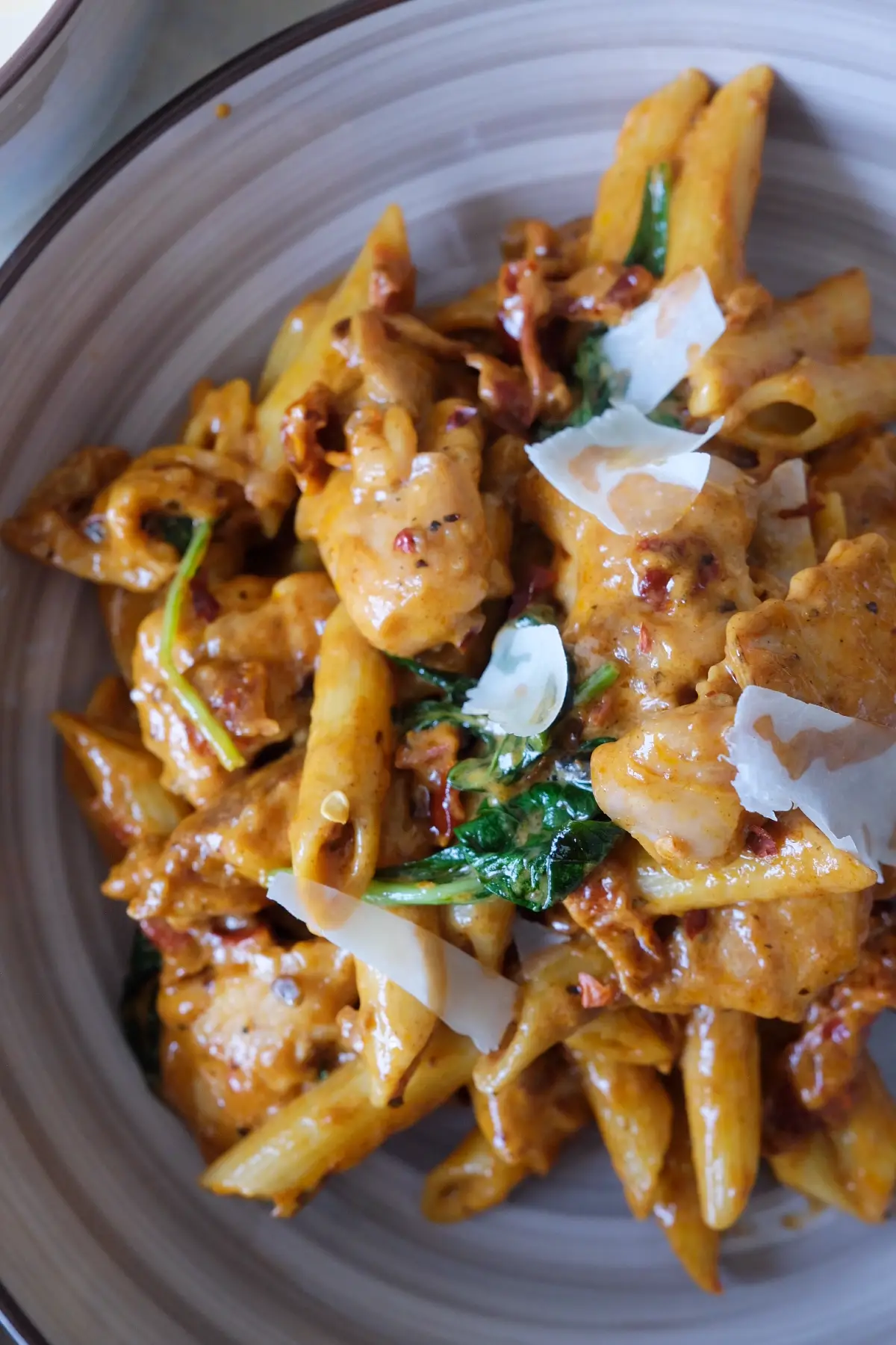 Plate of marry me chicken pasta with juicy chicken, creamy parmesan sauce, sun-dried tomatoes, and basil.