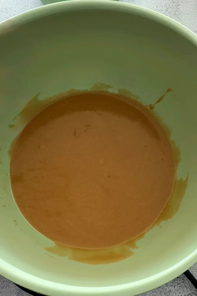 Melted butter, sugars, egg, and vanilla in a mixing bowl before whisking.