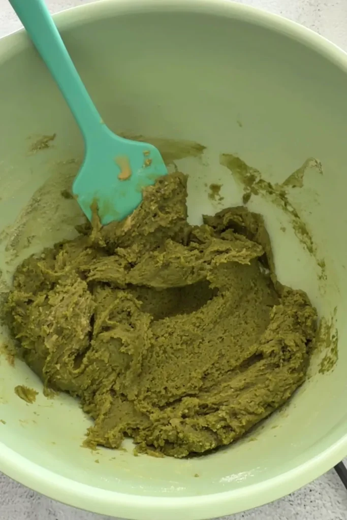 Thick matcha cookie dough fully mixed in a bowl with a spatula.