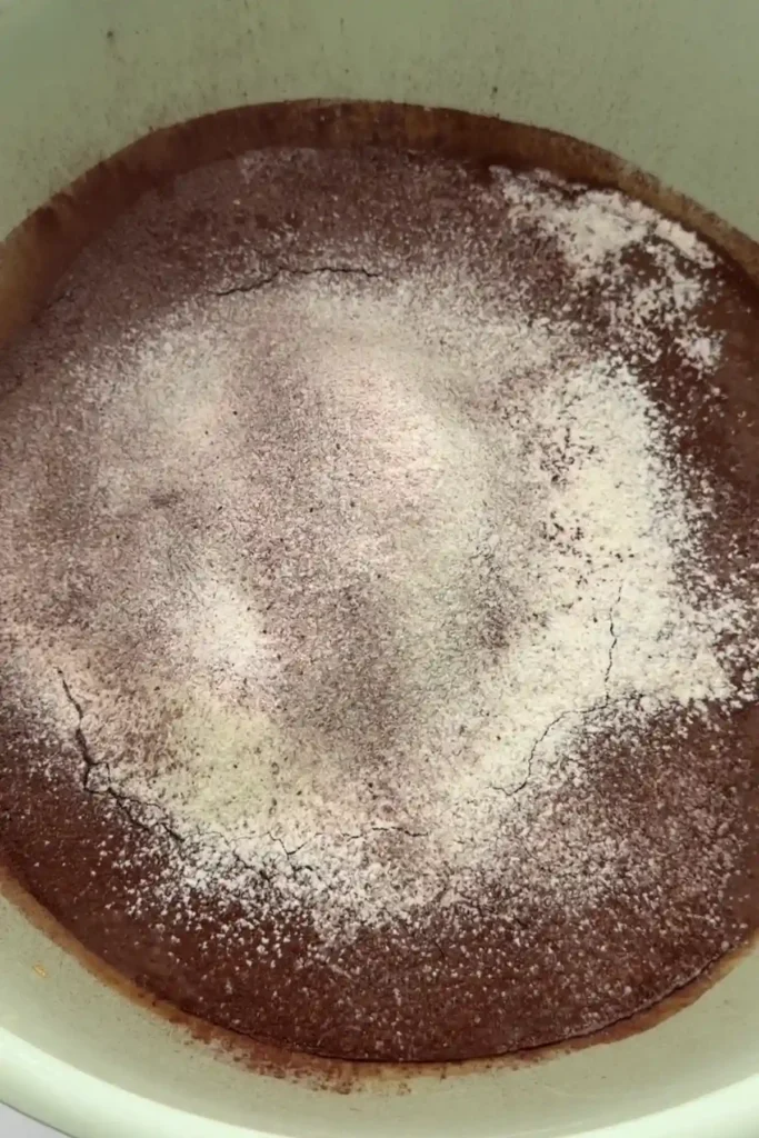 Dry ingredients sitting on top of wet brownie batter before mixing
