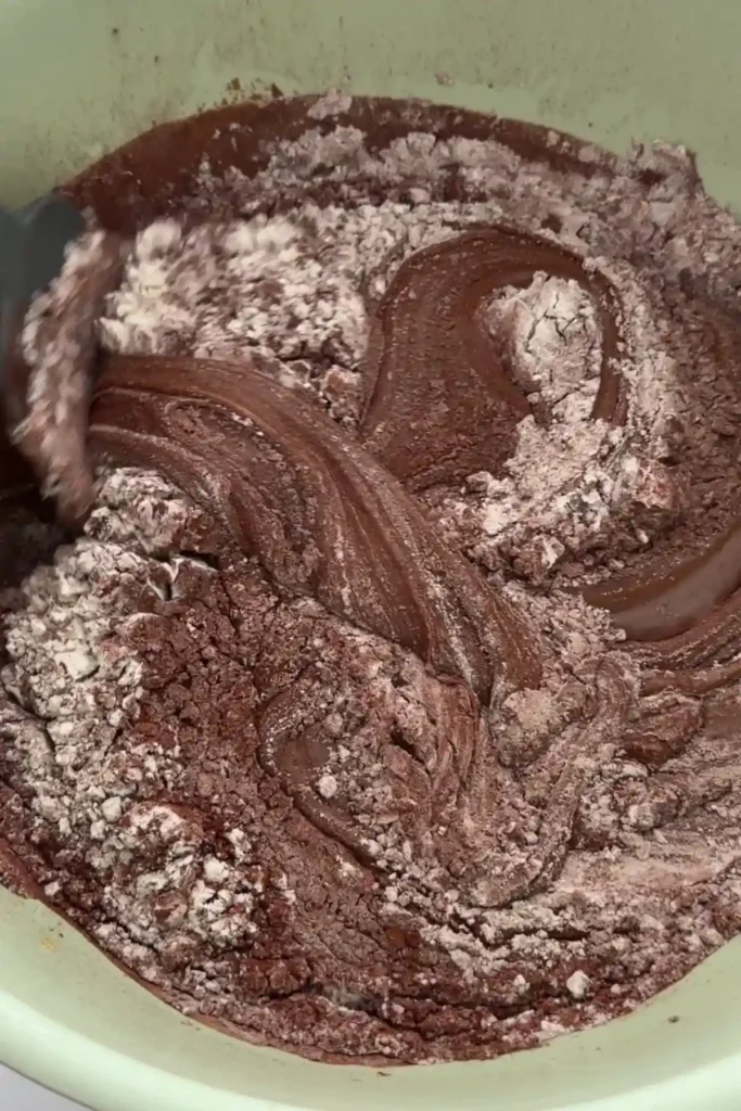 Folding dry ingredients into brownie batter until just combined