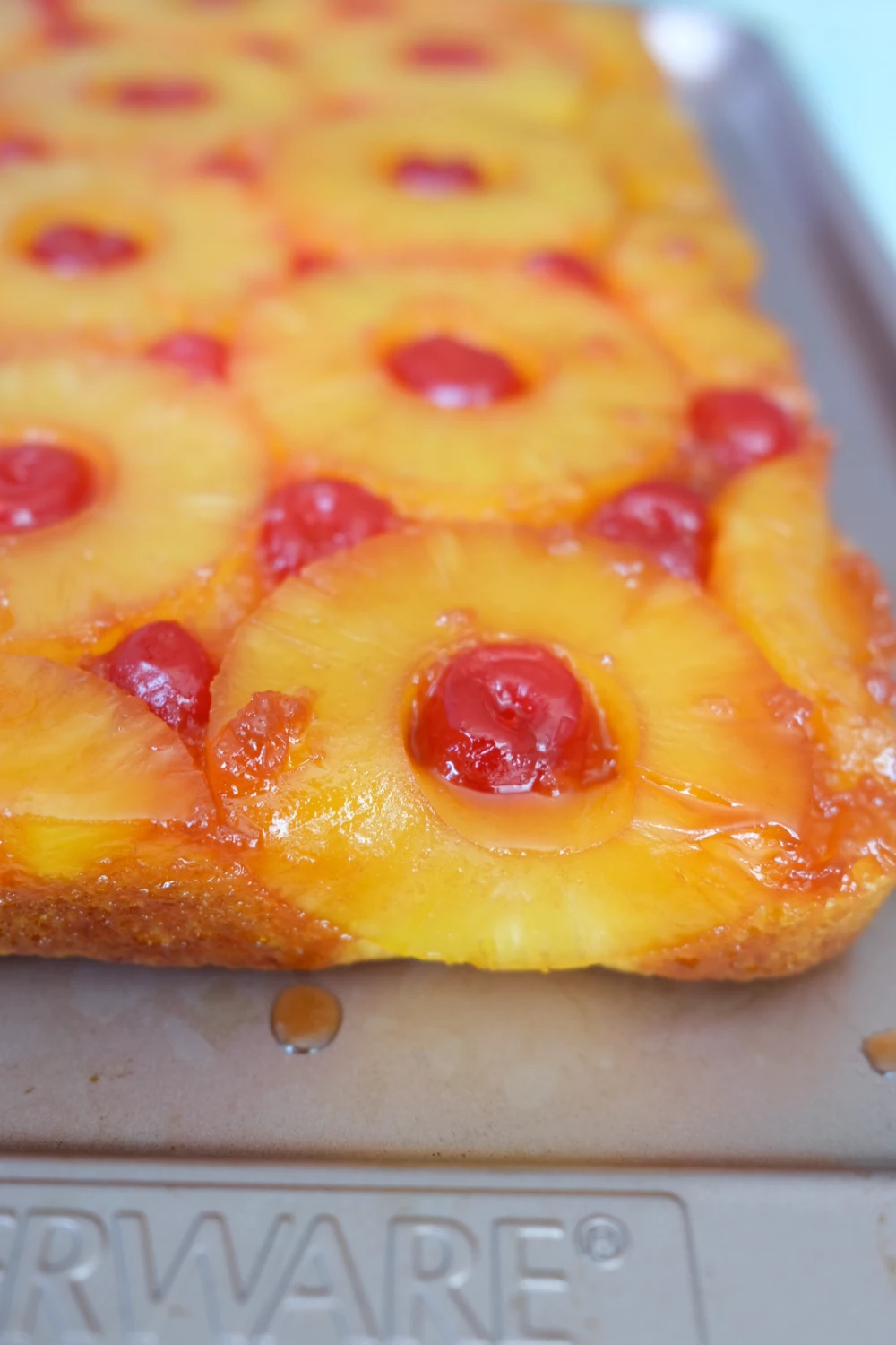 Pineapple upside down cake in a baking pan topped with caramelized pineapple rings and maraschino cherries