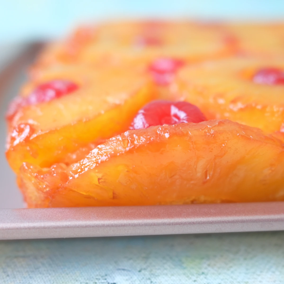 Close-up of pineapple upside down cake showing glossy pineapple rings and cherries on top