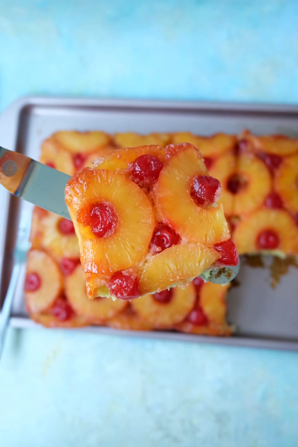 Pineapple upside down cake slice being lifted with a spatula showing moist yellow cake crumb