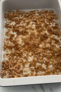 Brown sugar sprinkled over melted butter in a baking pan