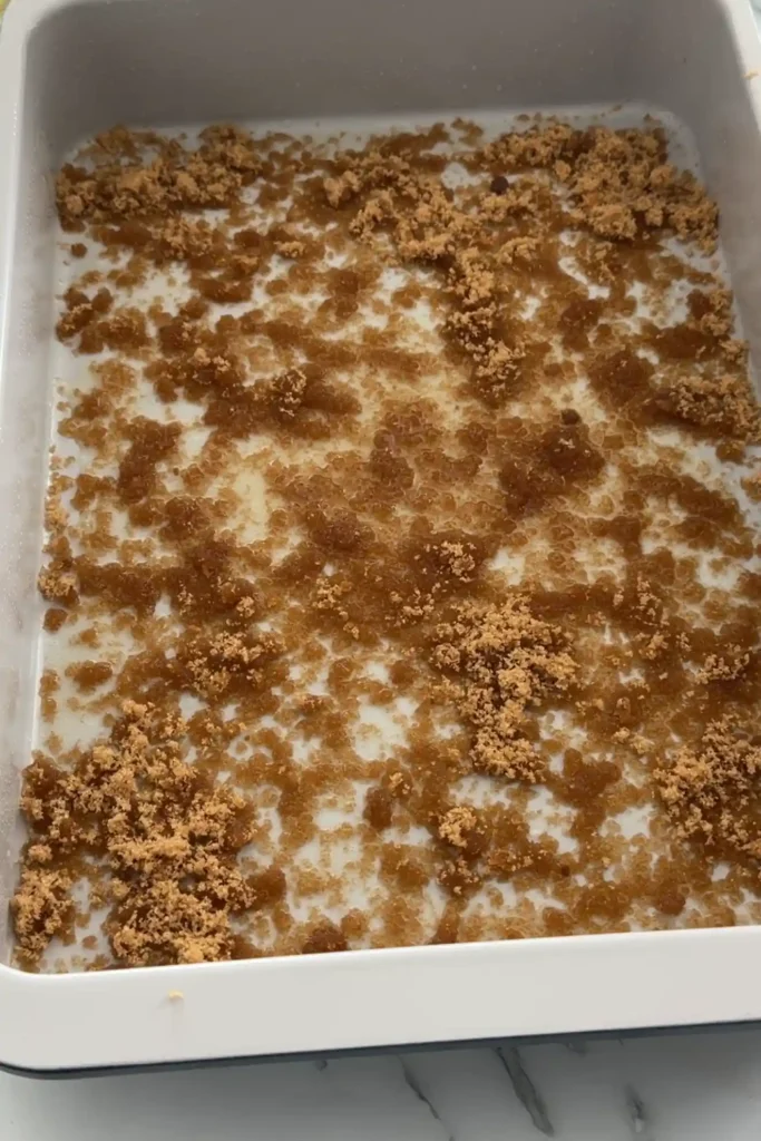 Brown sugar sprinkled over melted butter in a baking pan