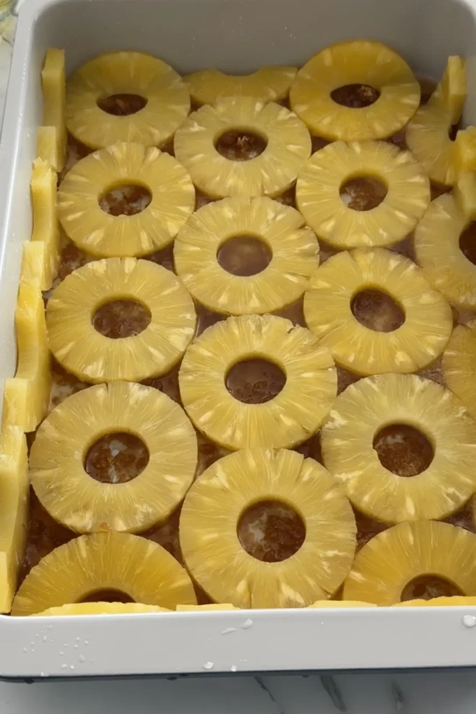 Pineapple slices arranged in the baking pan over brown sugar