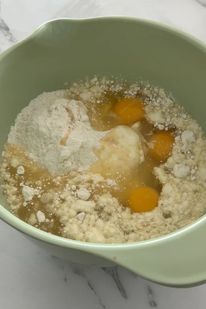 Yellow cake mix, eggs, oil, and pineapple juice in a mixing bowl before stirring