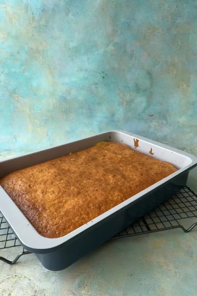 Freshly baked pineapple upside down cake in a 9x13 pan cooling on a wire rack