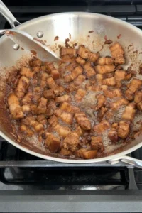 pork belly cooking with garlic and aromatics in a pan
