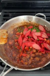 adding diced potatoes and carrots to pork menudo sauce