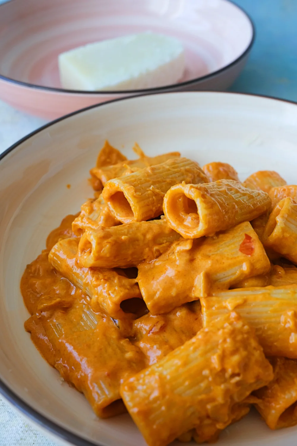 Close-up of spicy rigatoni with creamy orange sauce and visible red chili flecks.