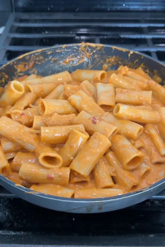 Rigatoni tossed in creamy spicy sauce in a skillet until fully coated.