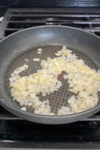 Softened onion and garlic cooking in olive oil in a skillet.