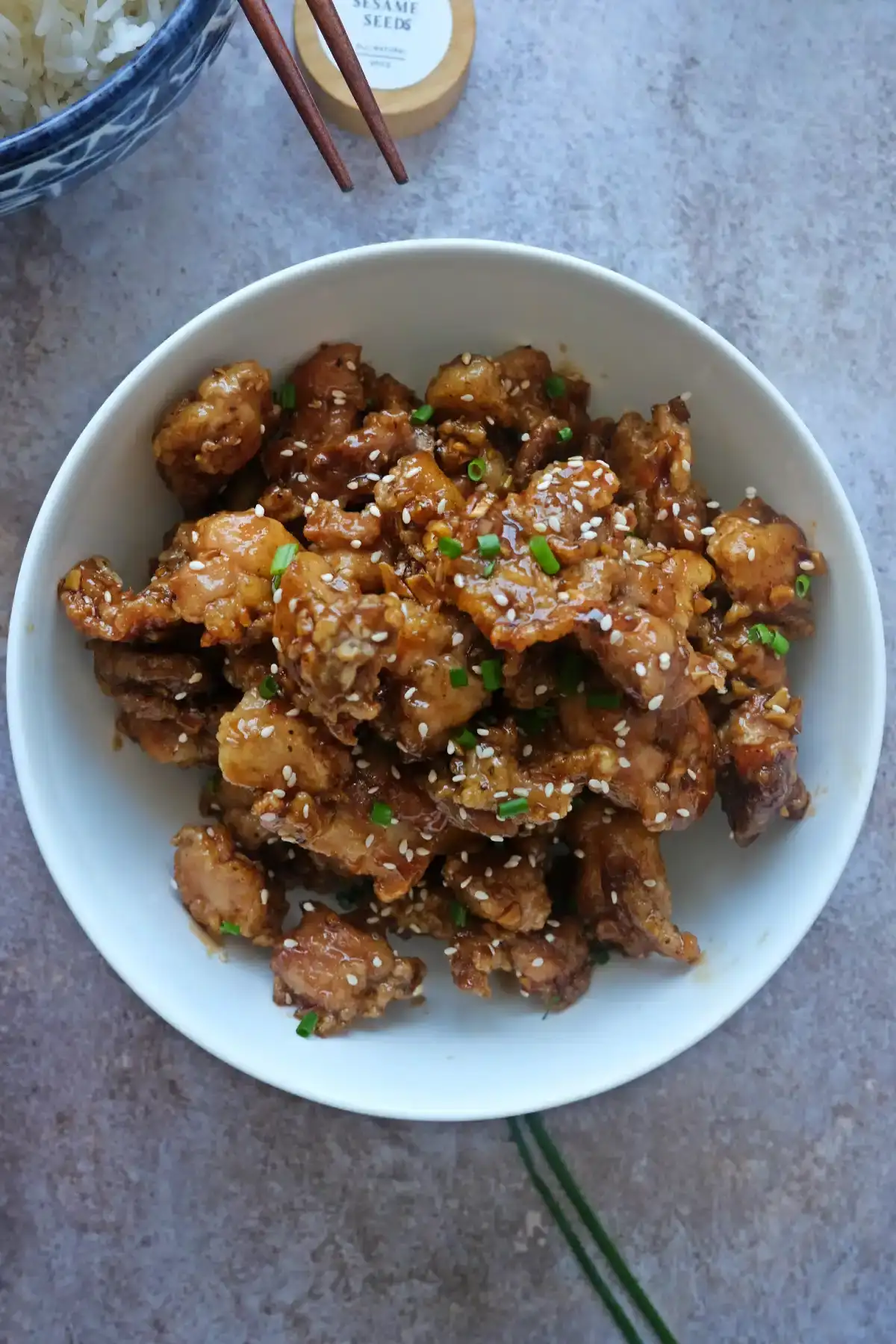 Top view of crispy honey garlic chicken bites coated in sticky sauce with sesame seeds