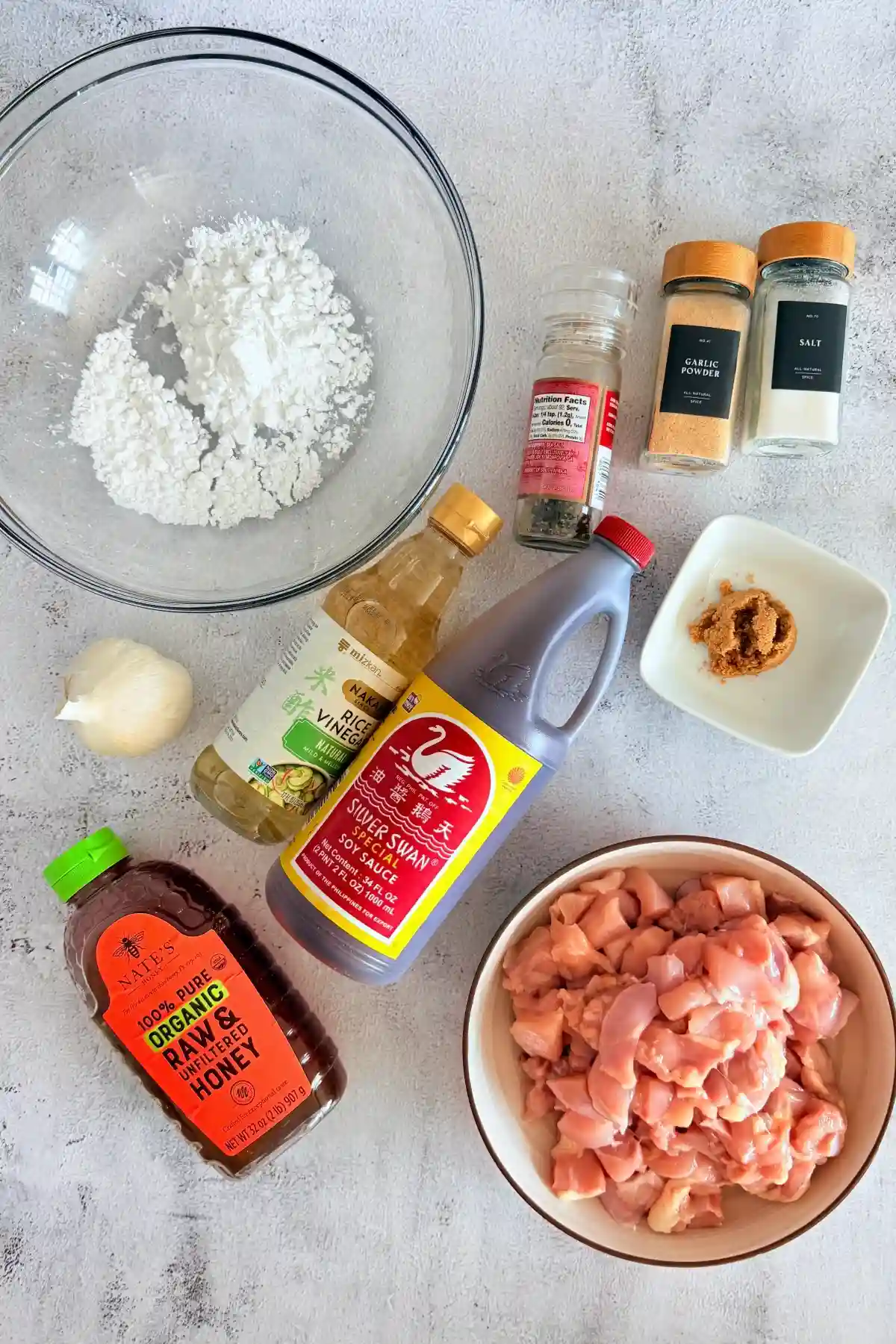 Ingredients for honey garlic chicken including chicken thighs, soy sauce, honey, garlic, and potato starch