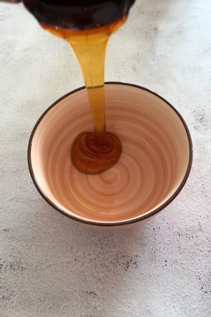 Honey being poured into a small bowl for sauce