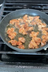 Golden brown fried chicken pieces crisping in oil