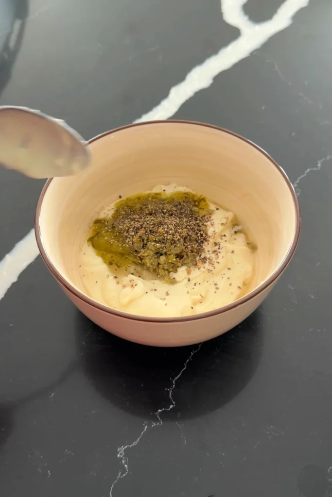Mayonnaise, relish, capers, and pepper in a bowl for homemade tartar sauce.