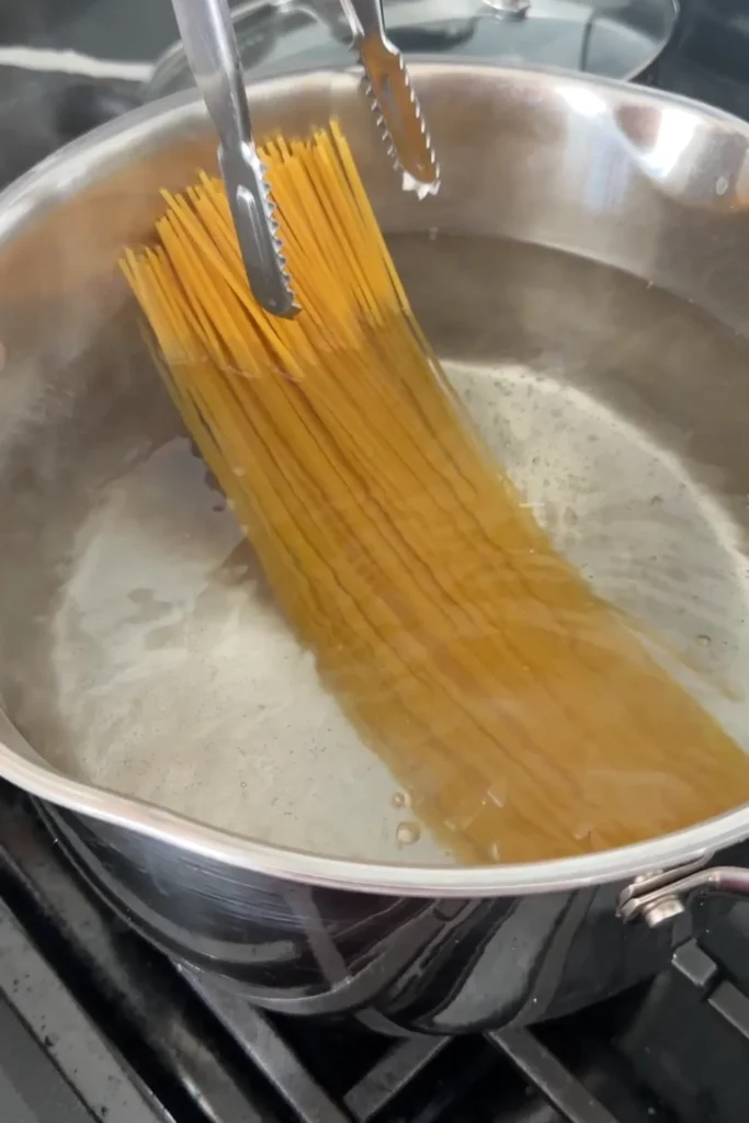 Dry spaghetti being lowered into a pot of boiling salted water.