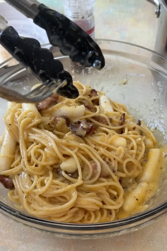 Spaghetti, tteokbokki, and bacon tossed together in creamy carbonara sauce.