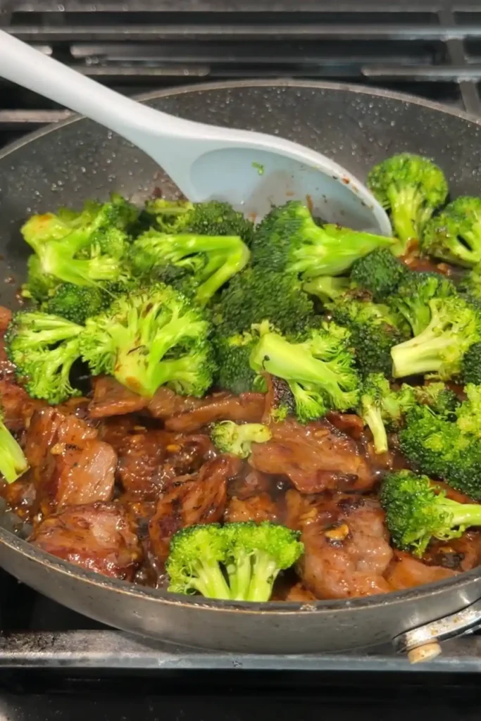 Beef simmering in a bubbling garlic-ginger sauce as it thickens in the skillet.