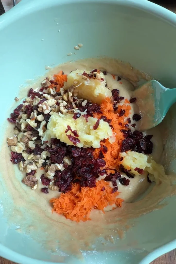 Grated carrots, crushed pineapple, chopped walnuts, and chopped dried  cranberries added to the carrot cupcake batter before folding together.