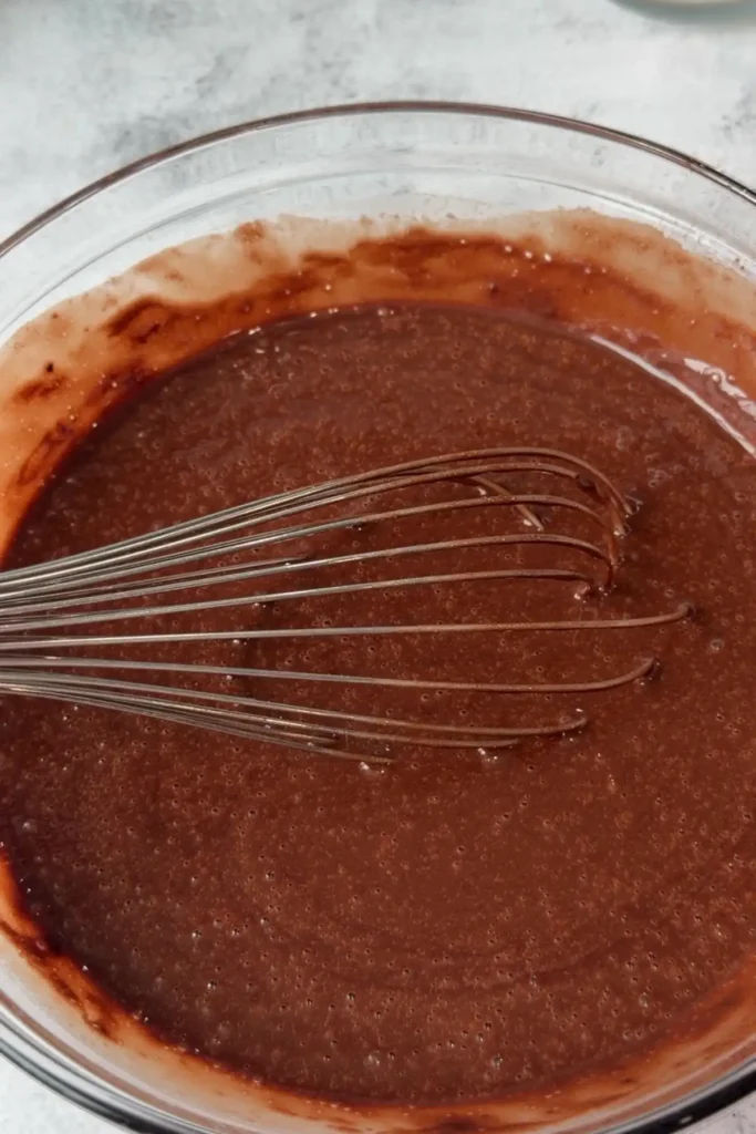 Fully mixed chocolate cake batter with a smooth, pourable consistency and small bubbles forming on the surface.