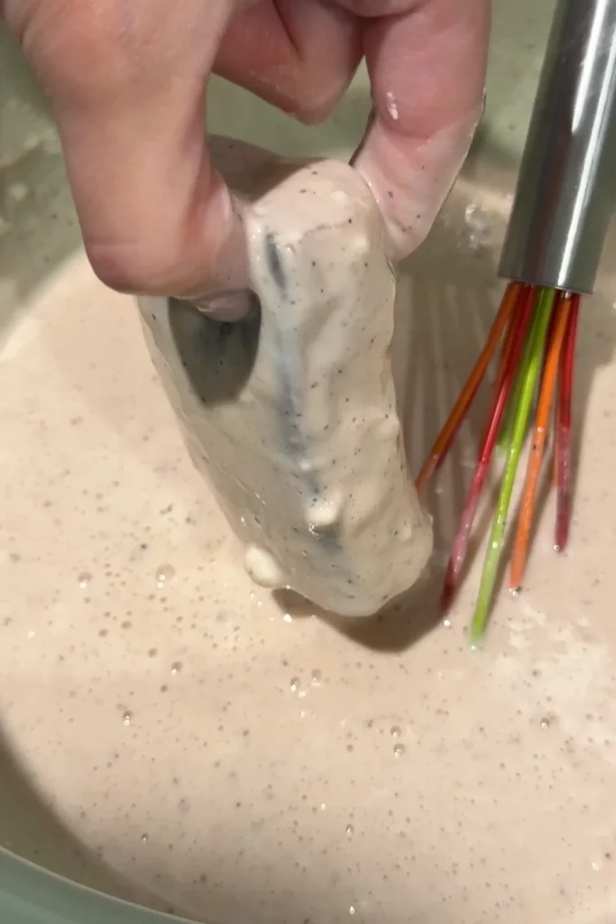 Cod fillet dipped into batter for frying