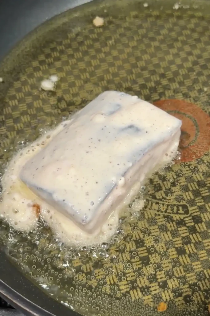 Battered cod fillet frying in hot oil until crispy