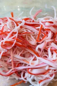 Close-up of shredded imitation crab in a clear glass mixing bowl